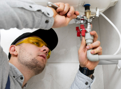 Homme avec lunettes réparant un chauffe-eau