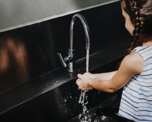 Little girl washing her hands in school.